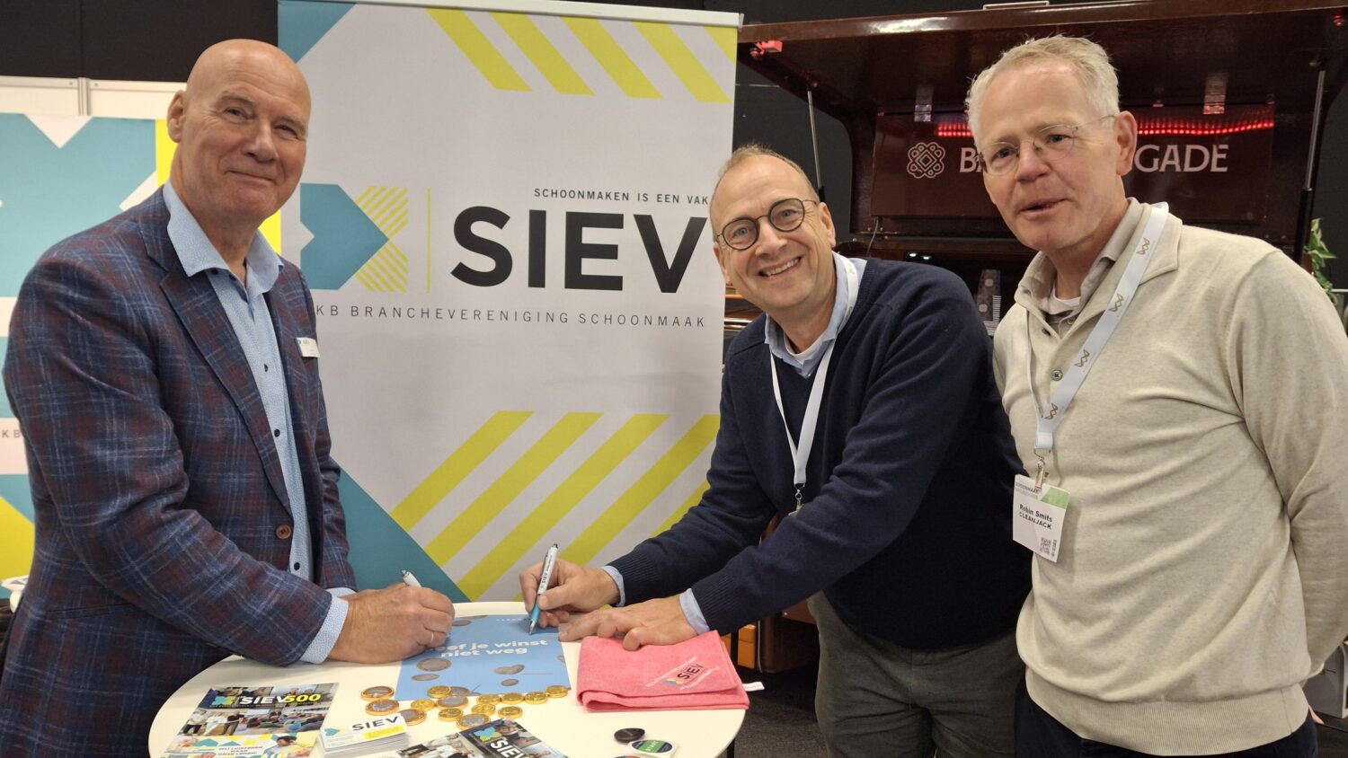 Robin Smits (rechts) kijkt mee als zijn collega Niels van den Berg samen met Paul Fok de samenwerking ondertekent.