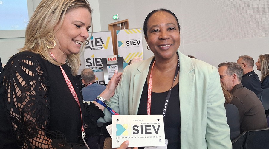 Rolien van Groeningen overhandigt het naambordje van SIEV aan Marijke Tevreden van Tevreden Cleaning.