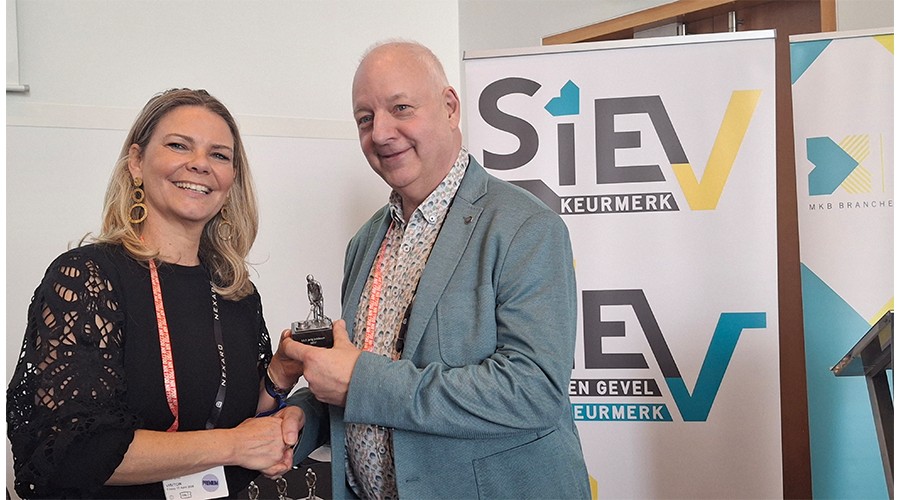 Mede-bestuurslid Rolien van Groeningen deelt aan Frank Verberne het beeldje uit dat hoort bij het 12,5 jarig lidmaatschap van zijn bedrijf.
